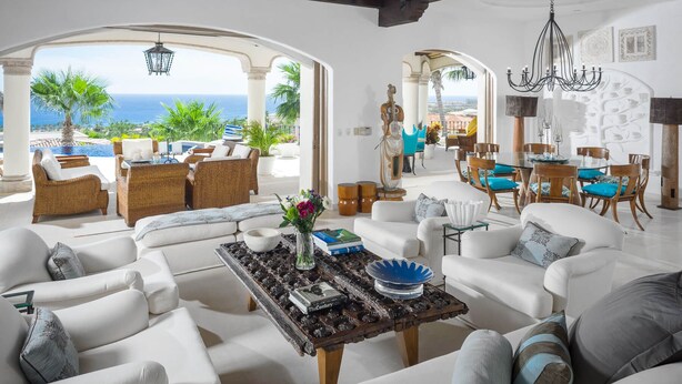 A spacious living room with white furniture, a coffee table, and a view of the ocean. - 2 FREE NIGHTS IN CABO at Villa Buena Vida! (Cabo Corridor)