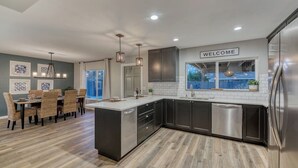 Una cocina moderna con armarios oscuros, una isla blanca y un letrero de bienvenida.