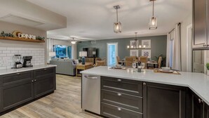 Una cocina moderna con armarios oscuros, una isla central, iluminación colgante y una zona de comedor con vistas.