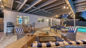 Un patio al aire libre con mobiliario de mimbre, una parrilla y una piscina.