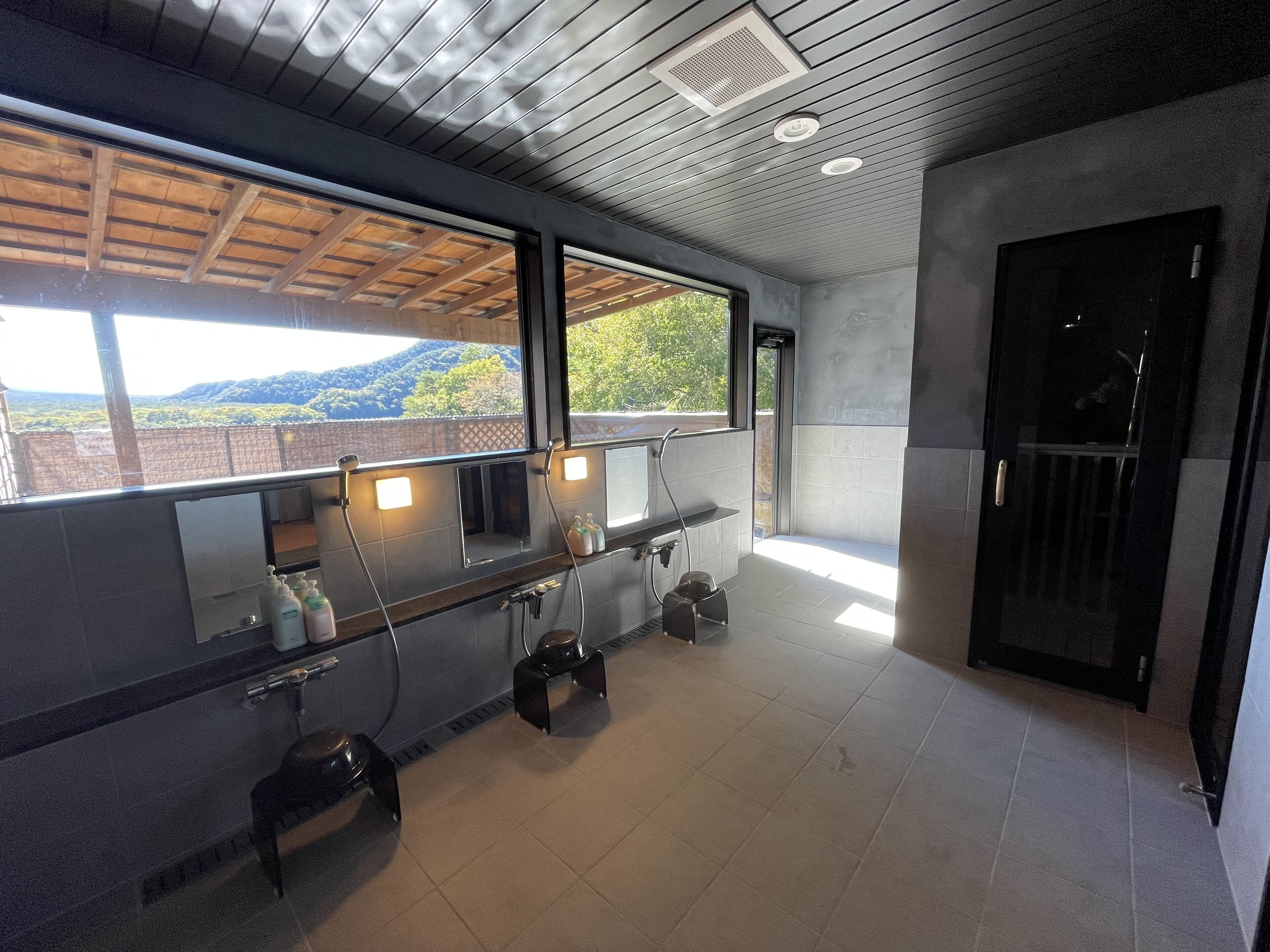 A modern bathroom with a large window, a shower area, and a toilet.