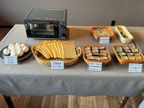 Un tavolo con diversi cibi, tra cui uova sode, pane tostato, marmellata e un tostapane.