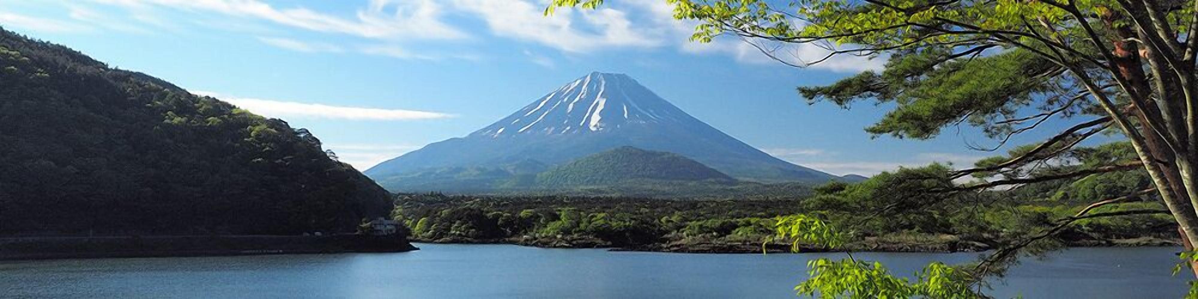 A mountain with a lake in the foreground and a forested area to the left.