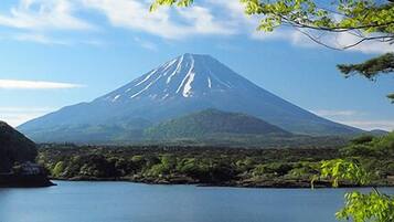 A mountain with a lake in the foreground and a forested area to the left.