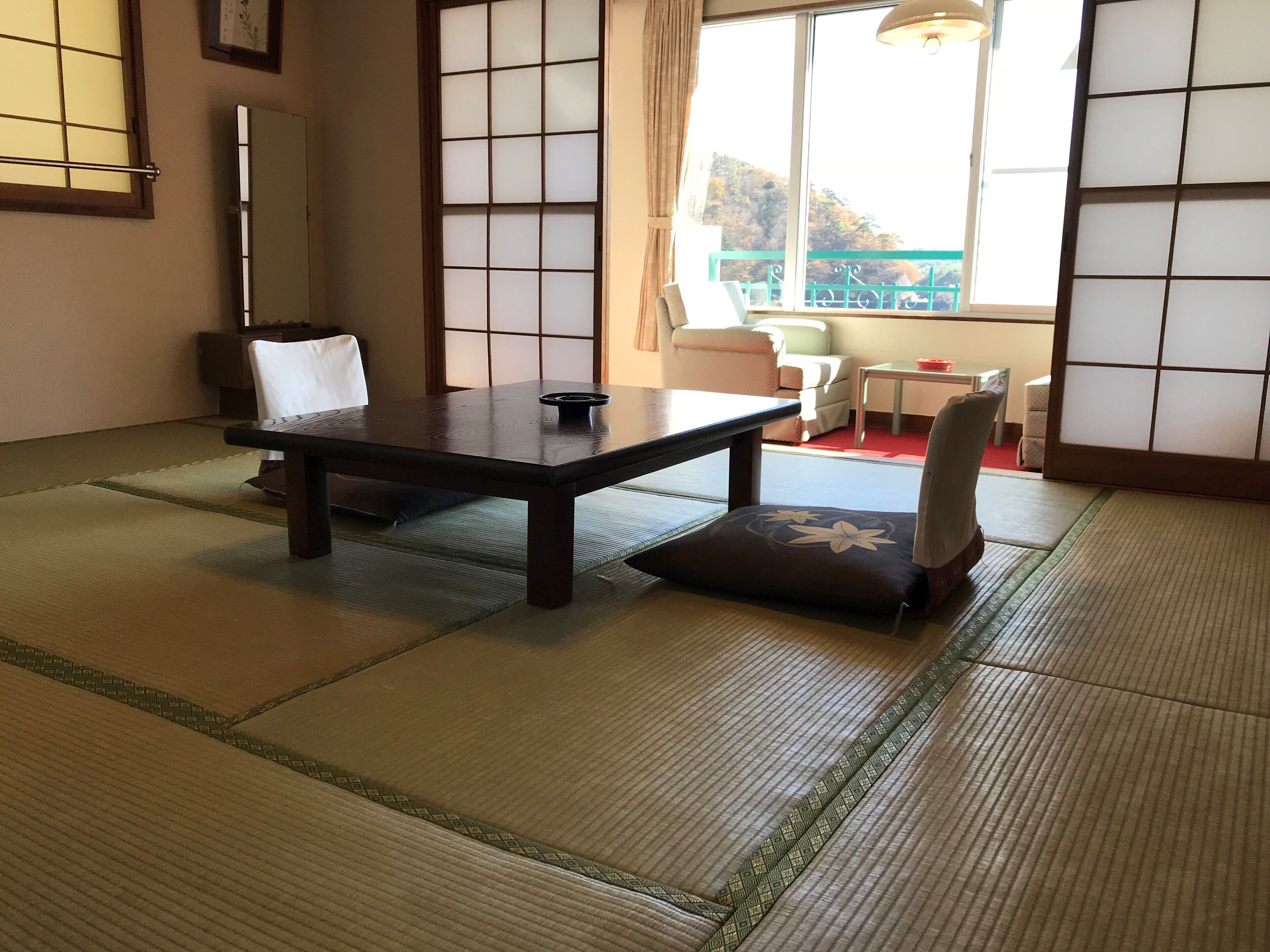 Une pièce de style japonais traditionnel, avec un sol recouvert de tatamis, une table basse et un fauteuil rembourré.