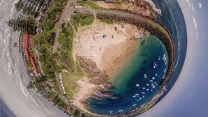 Een panoramisch uitzicht op een kustgebied met een zwembad, strand en jachthaven.