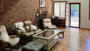 Een woonkamer met een bakstenen muur, leren banken, een glazen salontafel en een houten vloer.