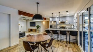 A modern kitchen with a central island, bar stools, and a dining area with a round table and chairs.