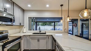 A modern kitchen with stainless steel appliances, a large island, and pendant lighting.