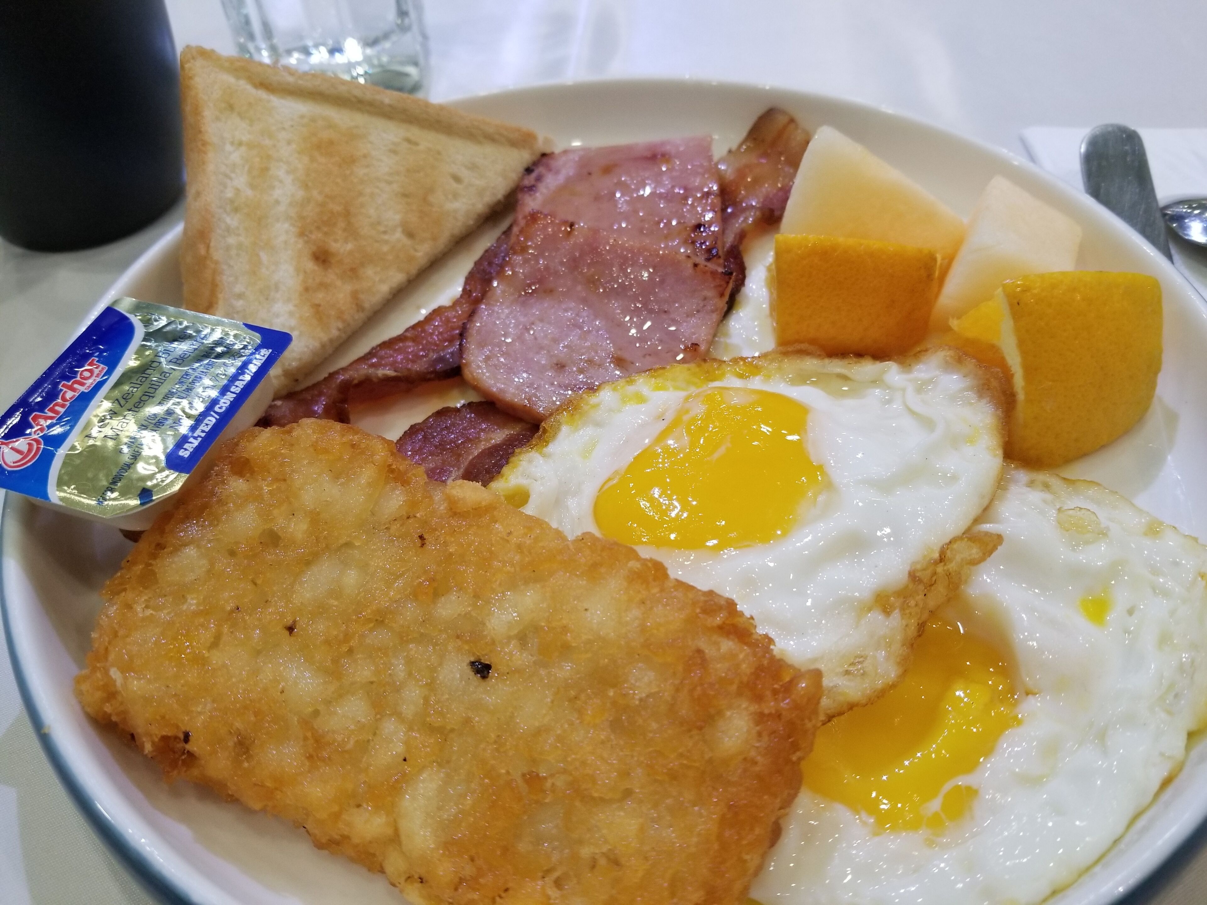 A plate of breakfast with toast, bacon, eggs, and cheese.