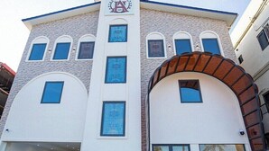 Ein Gebäude mit moderner Architektur, das ein markantes Logo oben, zahlreiche Fenster und einen großen Bogenportal aufweist.