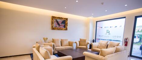 Een moderne hotel lobby met beige banken, een centrale salontafel en een groot raam met uitzicht.