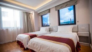 Ein Hotelzimmer mit zwei Betten, einem Fenster mit Blick und einem Nachttisch.