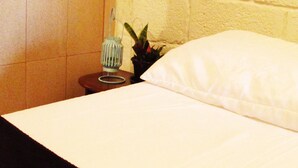 Un lit avec un oreiller blanc et une petite table placée à côté.