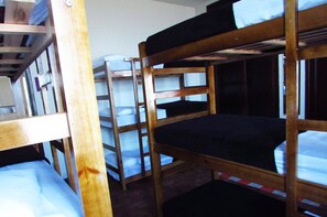 Dormitorio con literas de madera y ropa de cama blanca.