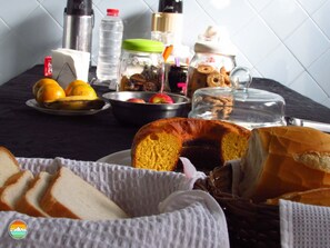 Una mesa con pan, bollería y frutas para el desayuno.