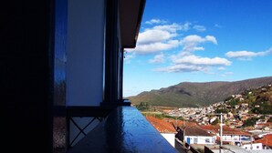 Une vue depuis une fenêtre donnant sur une ville, avec des bâtiments et une montagne en arrière-plan.