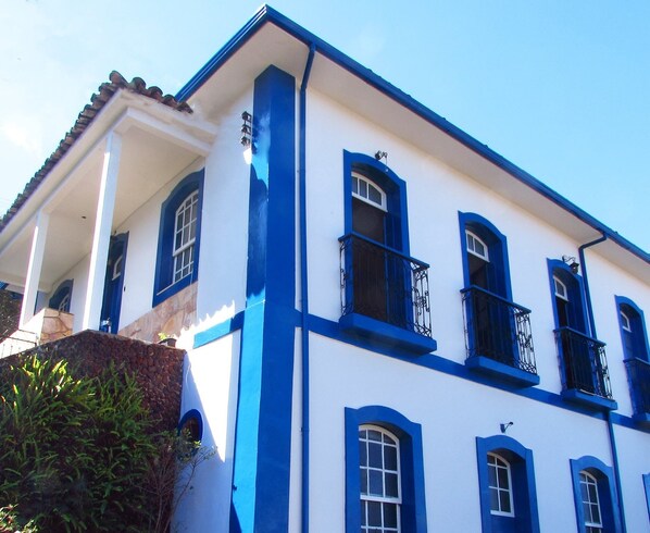 Un edificio con fachada blanca y detalles azules, con varias ventanas y balcones.
