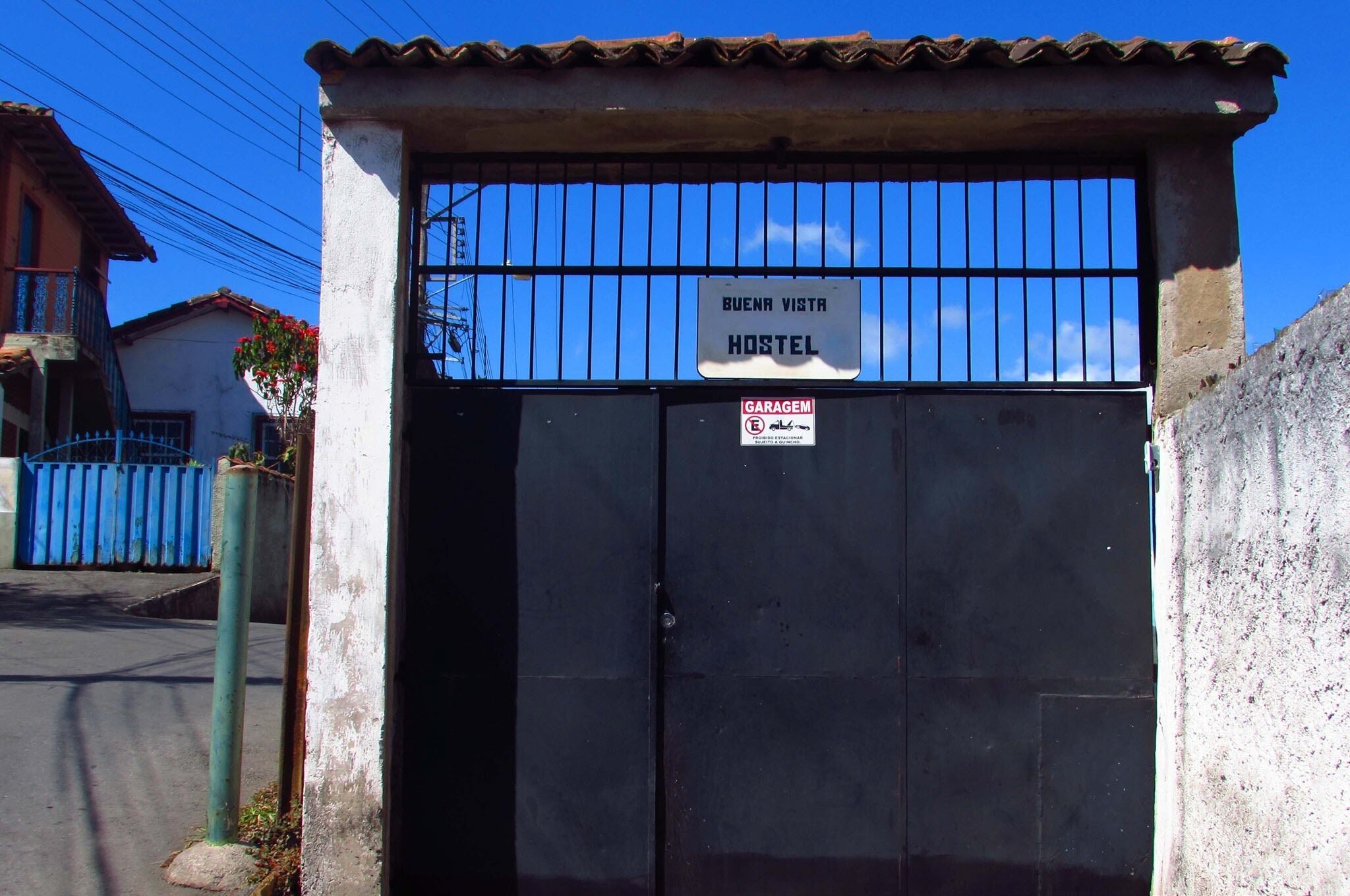 A hostel gate with a sign reading "BUENA VISTA HOSTEL" and a "GARAGEM" sign below it.