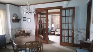 A dining room with a round table, chairs, a chandelier, and a door leading to another room. - Home is on the original 1926-1930 Route 66 alignment (Girard)