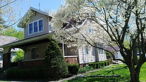 A two-story house with a covered porch and a well-maintained lawn. - Home is on the original 1926-1930 Route 66 alignment (Girard)