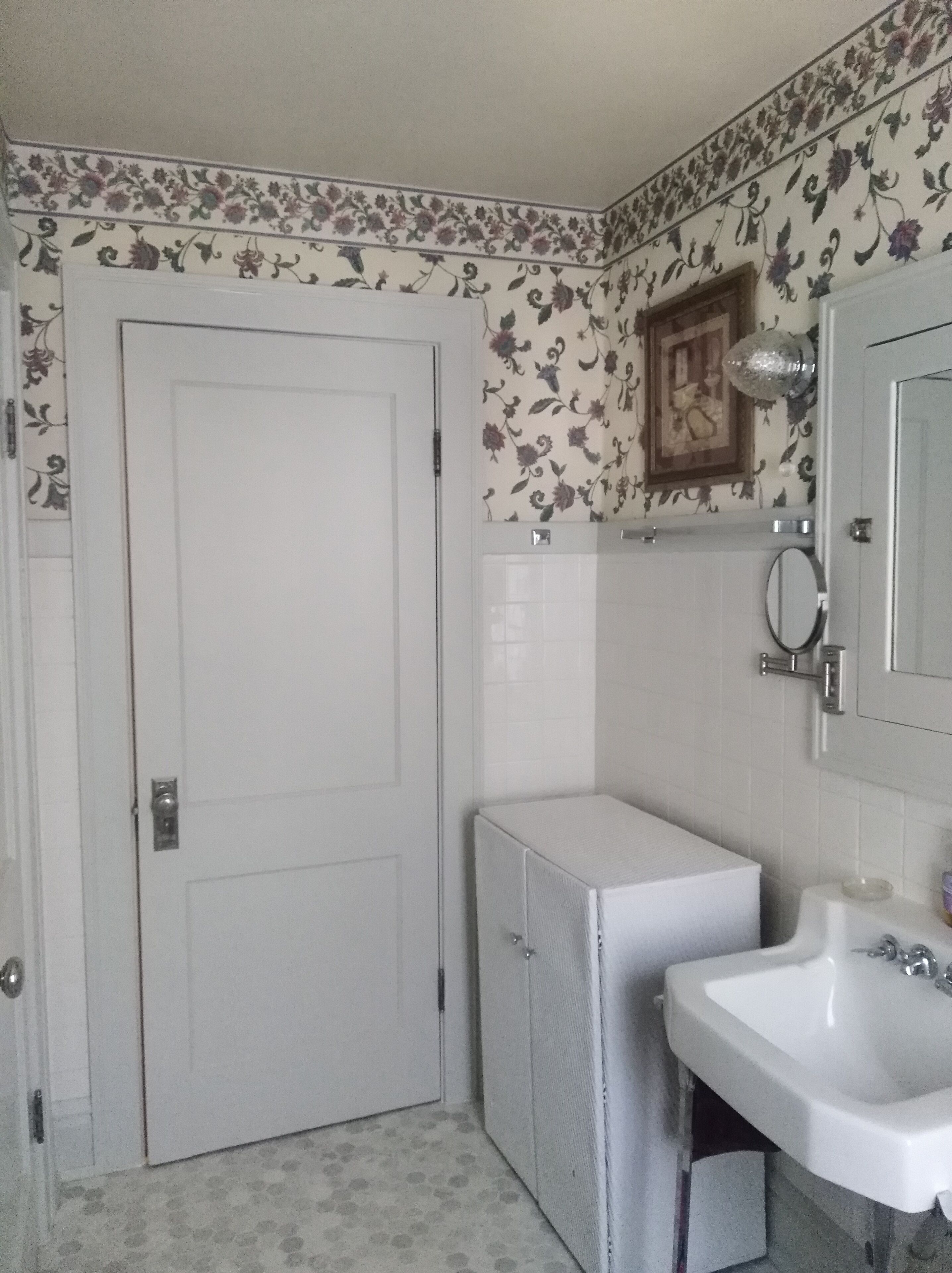 A bathroom with a white door, a white sink, and a mirror.