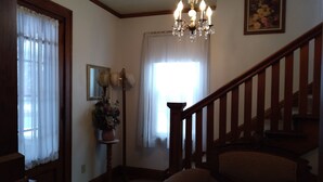 A staircase with wooden railings leading to an upper floor, a chandelier hanging from the ceiling, a potted plant, and a framed picture on the wall. - Home is on the original 1926-1930 Route 66 alignment (Girard)