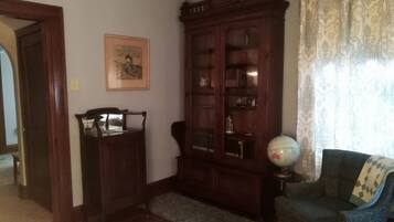 Una stanza con un armadio in legno, un mappamondo su un tavolino e un quadro appeso al muro.