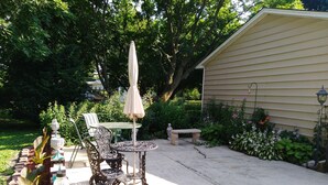 A patio with a table and chairs, surrounded by plants and a brick border. - Home is on the original 1926-1930 Route 66 alignment (Girard)