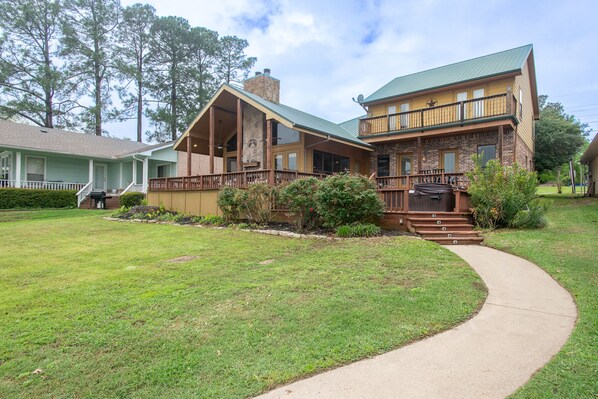 A two-story house with a stone chimney, a balcony, and a well-maintained lawn.