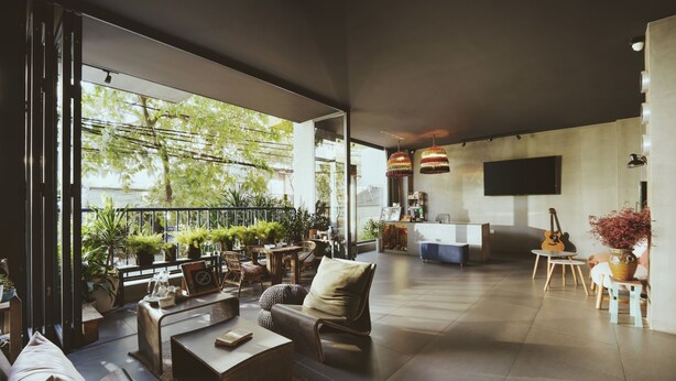 A spacious living area with a large window, a flat-screen TV, and a dining area with a table and chairs. - La Maison Des Delices (Da Nang)