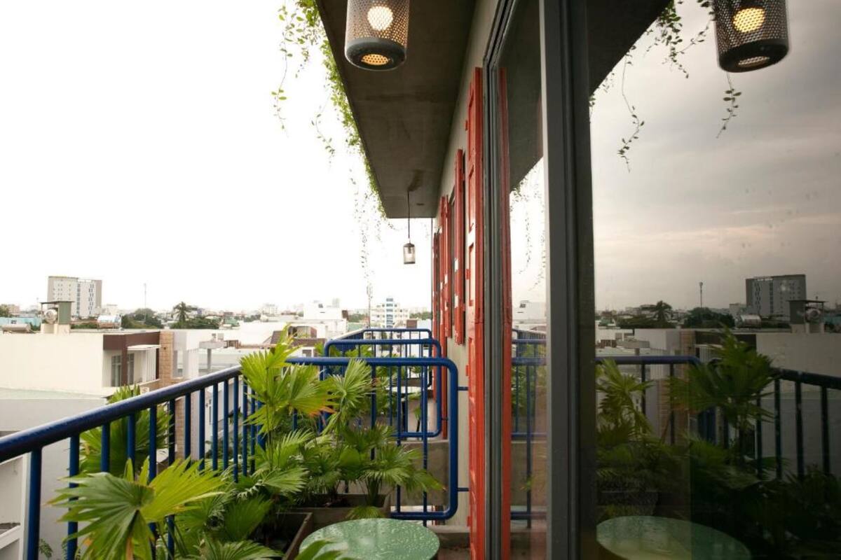 A balcony with a view of the city, potted plants, and a glass table.