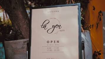 A signboard for 'la yen kafé' indicating it is open every day from 6:00 to 22:00, located on the 6th floor, 44-46 Mon Thien, Da Nang.
