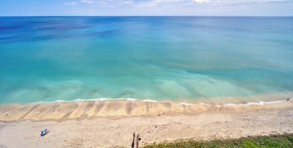 Une plage à l’eau turquoise et limpide, bordée d’un rivage sablonneux.