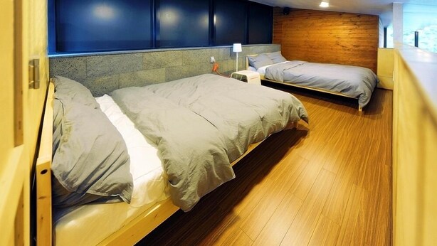 A room with two beds, wooden flooring, and a blue wall. - Haeyeorim Village (Yeoju)