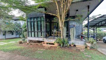 A modern house with a large glass window, a tree in front, and a car parked nearby.