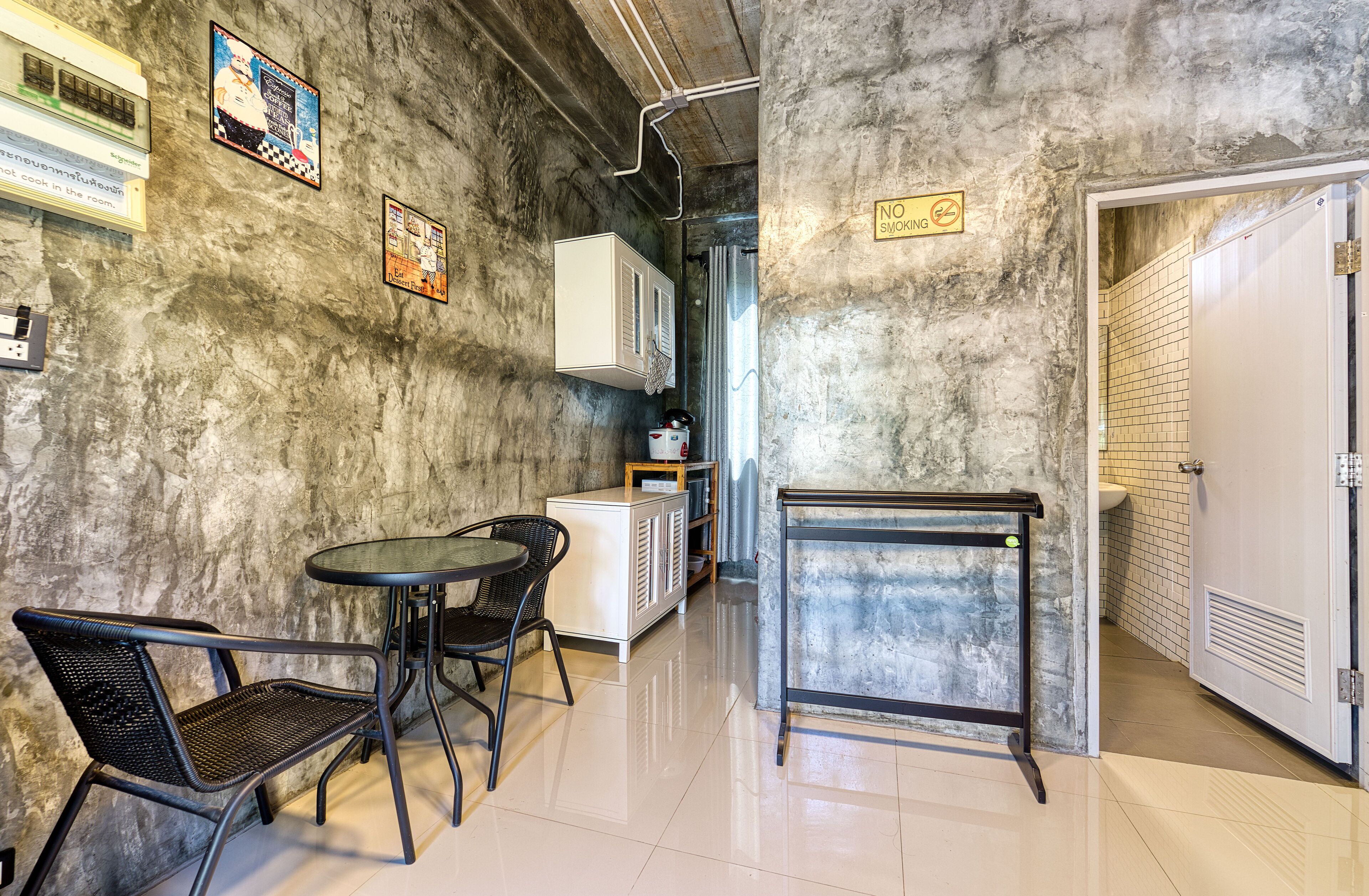 A small kitchenette with a table and chairs, a refrigerator, and a microwave. There is a 'No Smoking' sign on the wall.