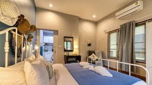 Una cama bien hecha con ropa de cama blanca y azul, una mesita de noche con una lámpara y una ventana con cortinas.