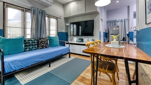 Un espacio habitable compacto con sofá, mesa de comedor y kitchenette.