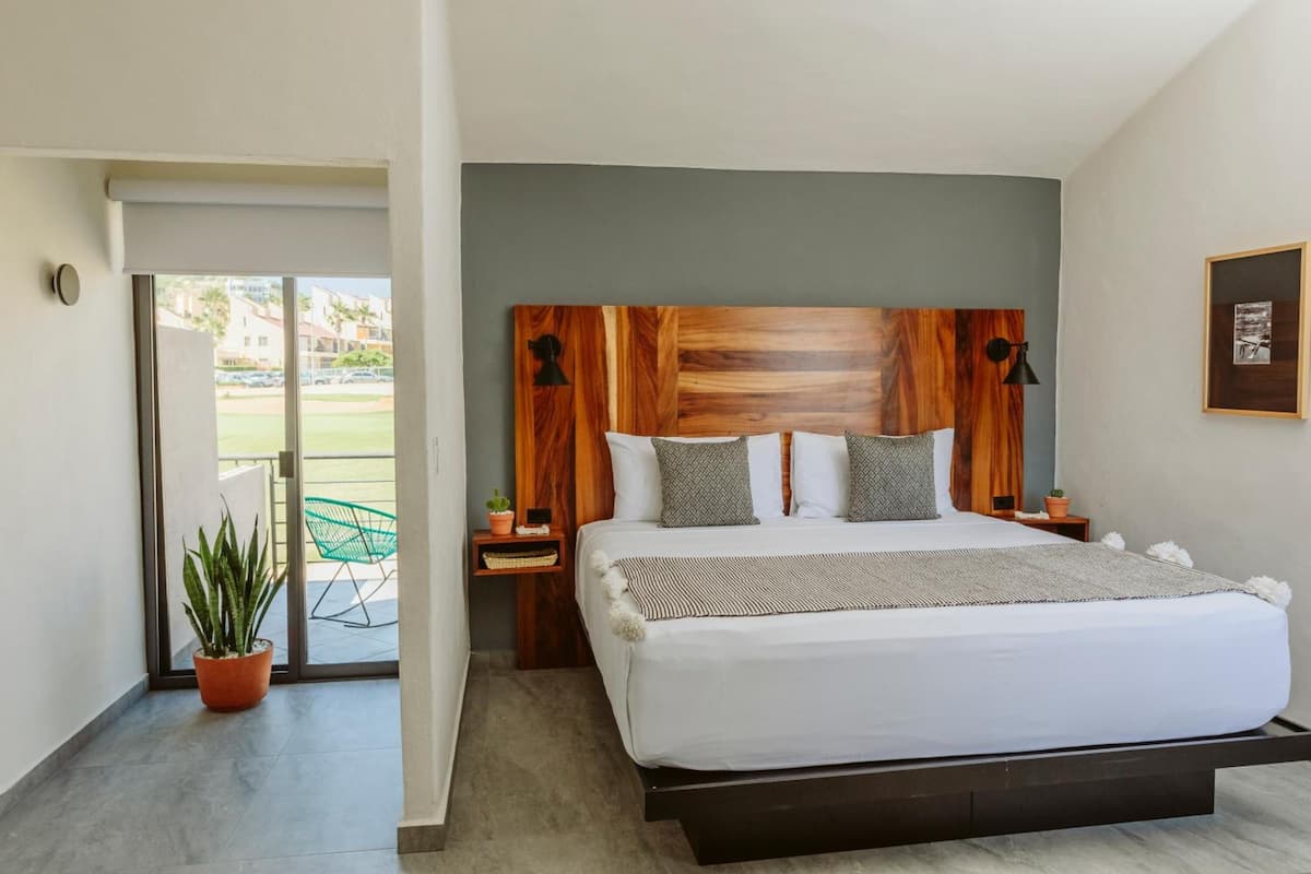 A modern bedroom with a large bed, wooden headboard, and a view of the outside.