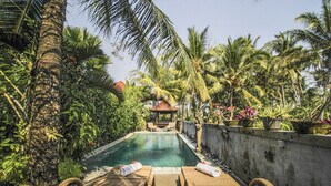 A pool area with lounge chairs and a gazebo surrounded by palm trees. - Villa Di Sawah Pejeng (Ubud)