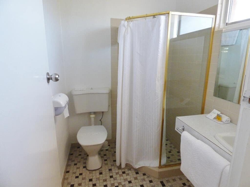 Un baño pequeño con inodoro, ducha y lavamanos.