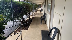 A covered corridor with benches, railings, and potted plants.
