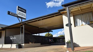 A motel with a covered parking area, a sign indicating vacancy, and a motor inn sign.