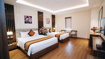 A hotel room with two beds, a desk, a chair, a TV, and artwork on the walls.