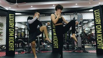 Une salle de sport équipée d’un ring de boxe, de machines de musculation et d’un mur recouvert de miroirs.