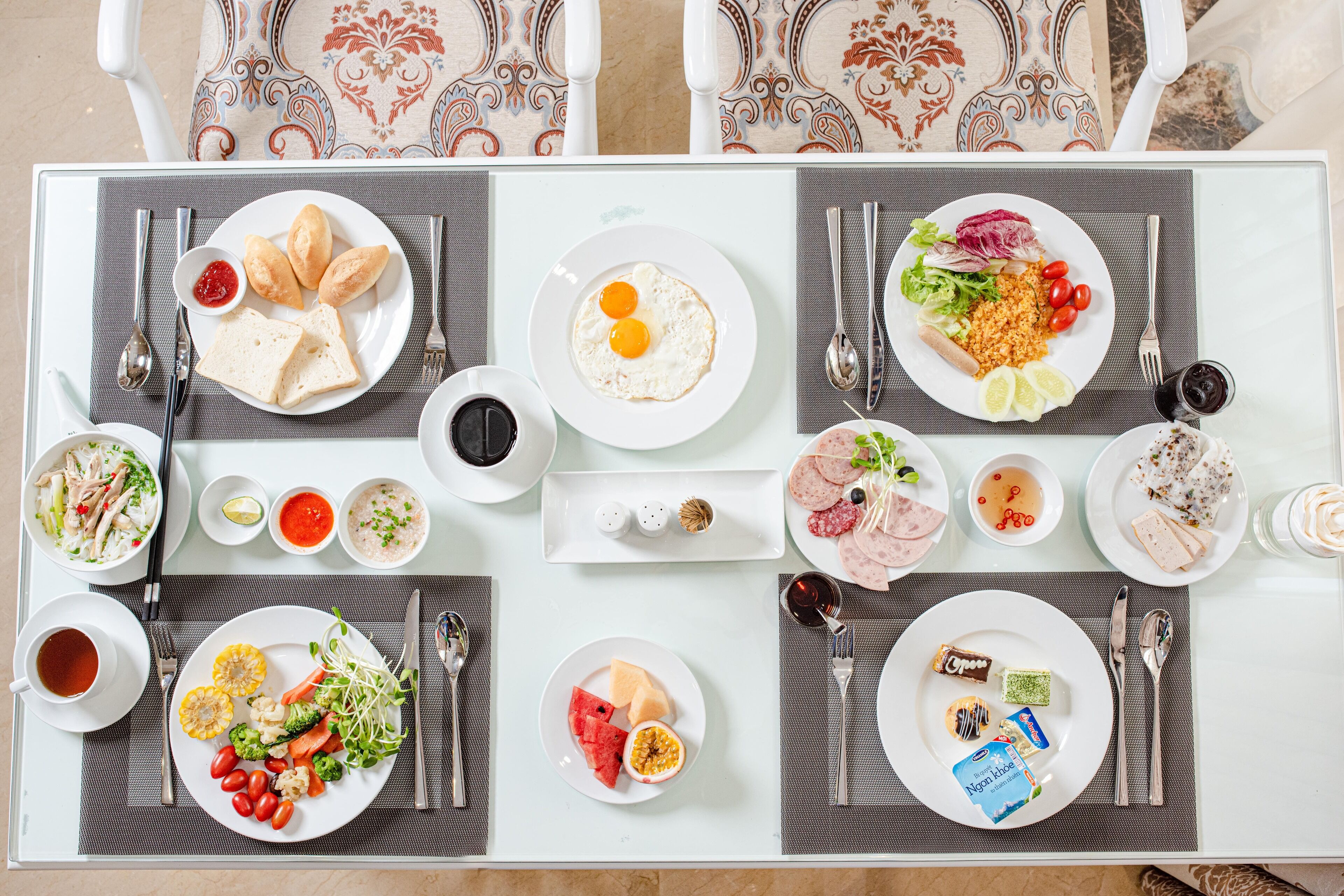 Une table à manger joliment dressée, avec différents plats, notamment des œufs, des légumes et de la viande, disposés sur des sets de table.