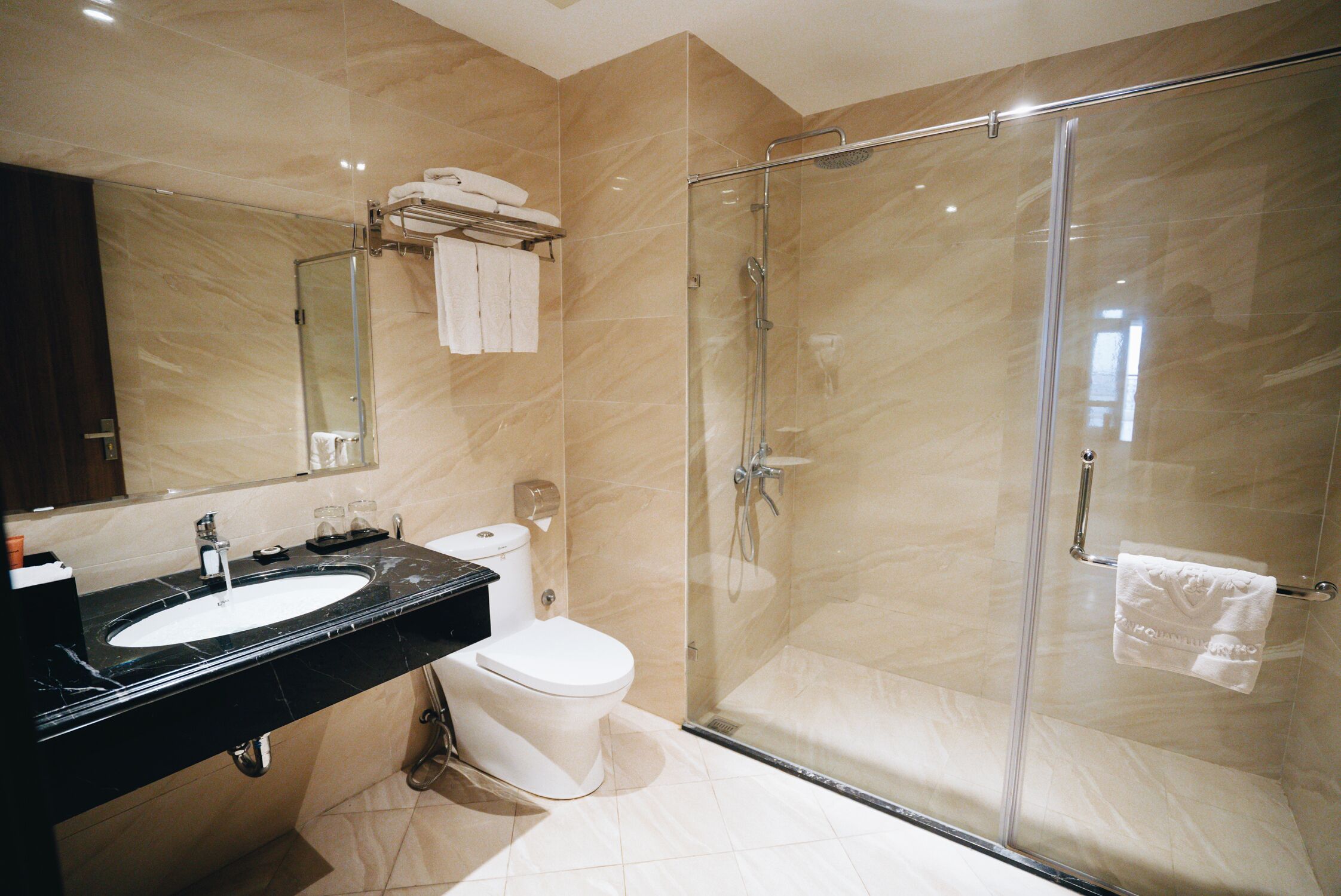 Une salle de bain moderne avec une douche à parois de verre, un lavabo noir et des toilettes.