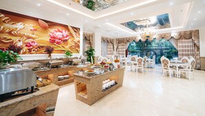 Een ruime hotel lobby met een buffetgedeelte, stijlvolle zithoek en een grote bloemenmuur.