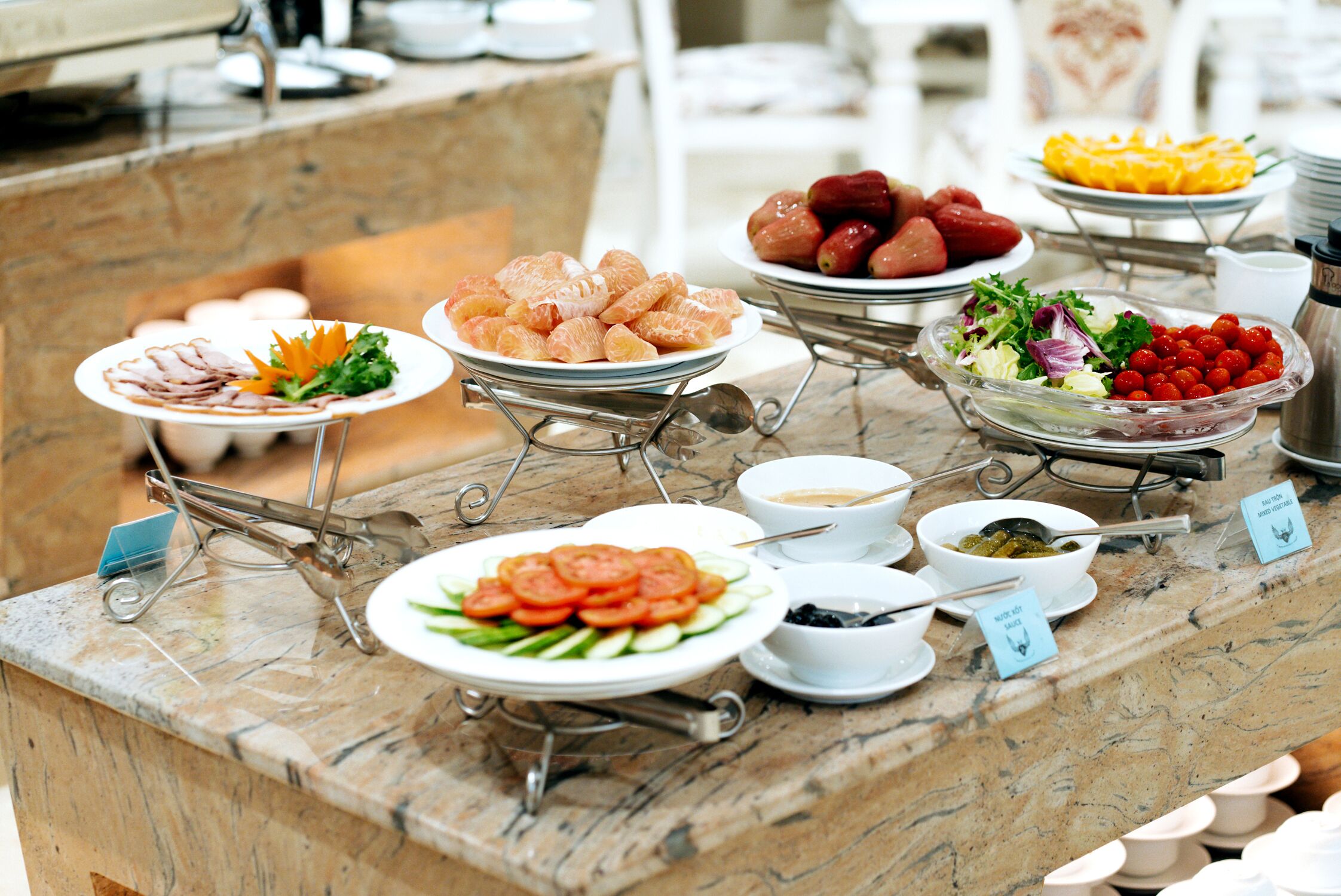 A buffet with various food items including sliced meats, fruits, and vegetables.